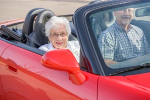 A convertible car with an elderly couple driving it, after recent Windshield Replacement in Galesburg IL