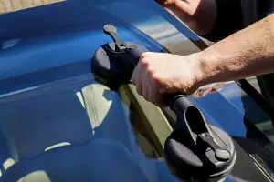 A team member of Glass Specialty WLC, a Window Company in Galesburg IL, repairs broken glass in a car.