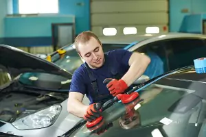 A team member of Glass Specialty WLC, a Window Company in Macomb IL, puts a new window in a car